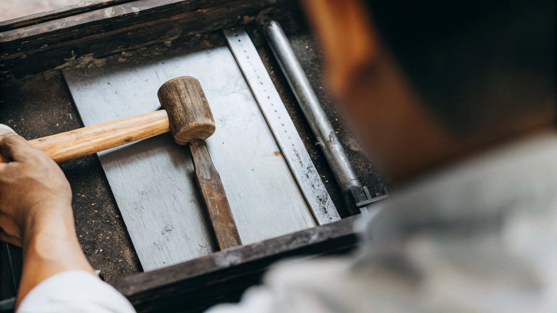 Hand carefully inspecting the grain and finish of a wooden hammer handle