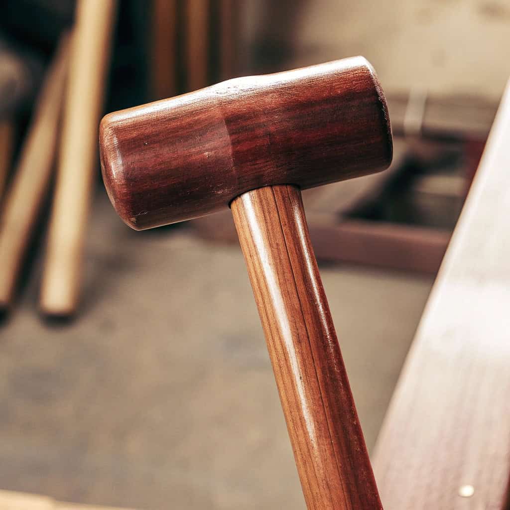 Selection of replacement wooden hammer handles next to various hammer heads