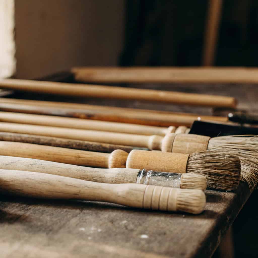 Unfinished wooden paintbrush handle alongside oils and waxes